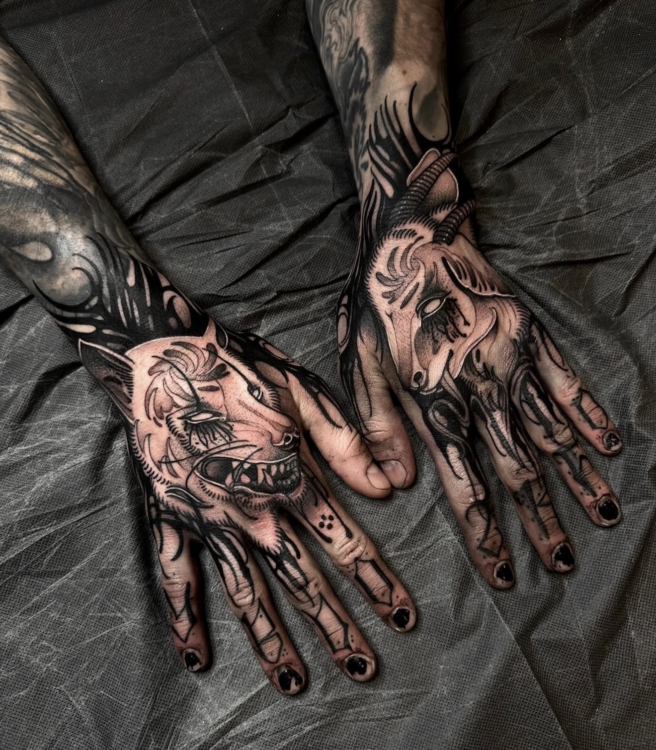 gothic blackwork tattoos covering both hands with dark organic shapes, demonic imagery and heavy black ink