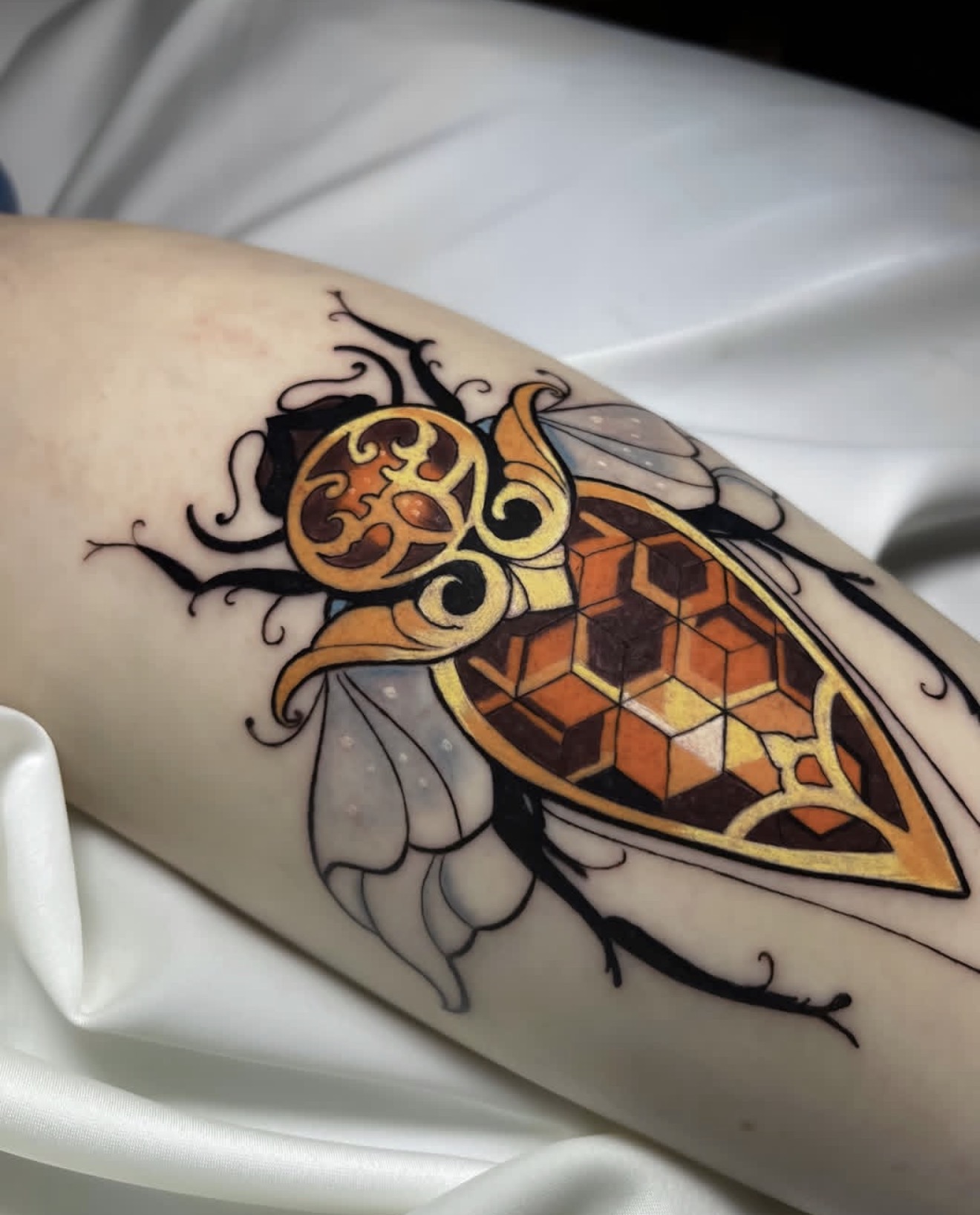 illustrative color tattoo of an ornamental insect with geometric patterns, warm tones and fine line details