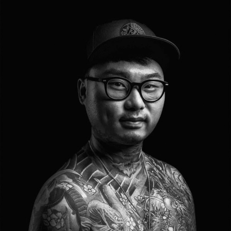 Kento, Japanese style tattoo artist at MT Tattoo Collective, wearing glasses and cap with full body irezumi tattoos