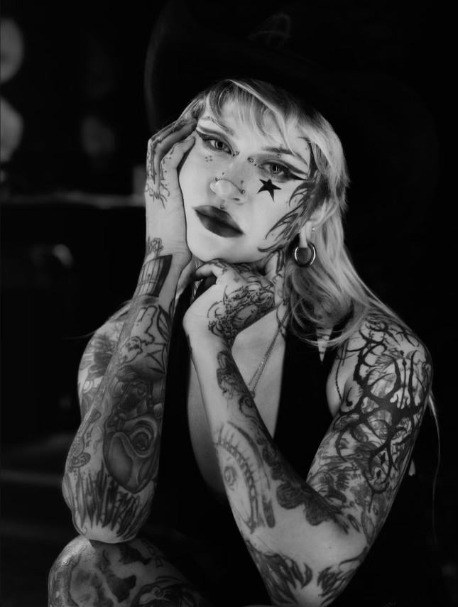 Nada, tattoo artist at MT Tattoo Collective Denver, black and white portrait with star face paint and hat