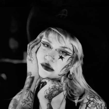Nada, tattoo artist at MT Tattoo Collective Denver, black and white portrait with star face paint and hat