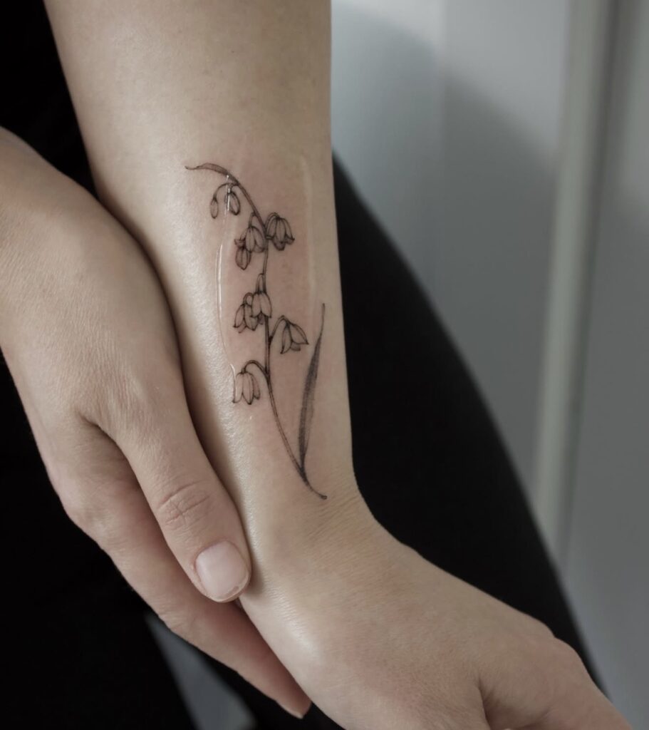 Fine line botanical flower tattoo on forearm